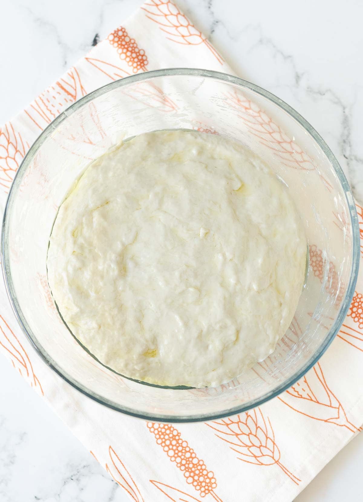 Bread dough in a glass mixing bowl.