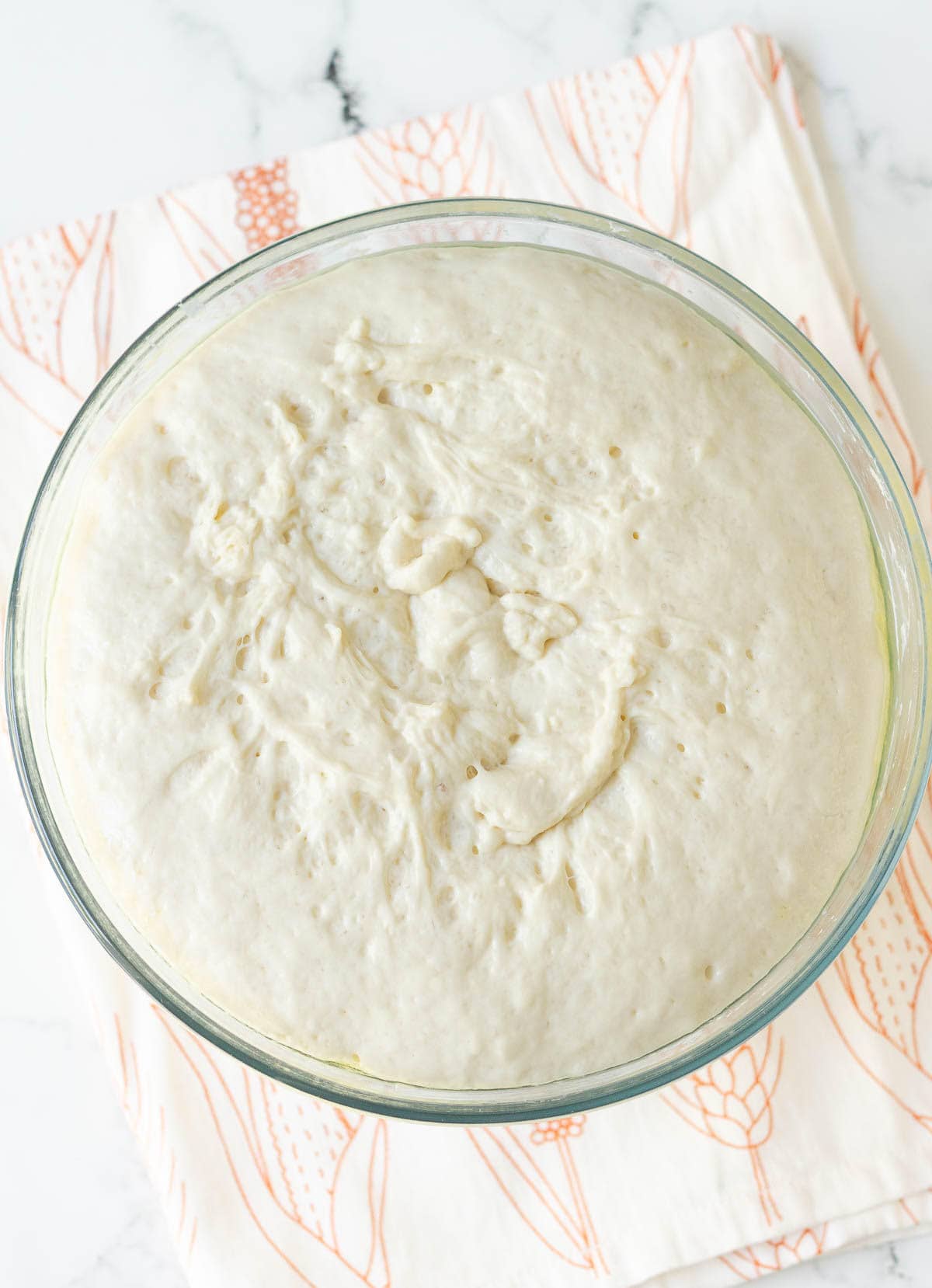 Proofed bread dough in a glass mixing bowl.