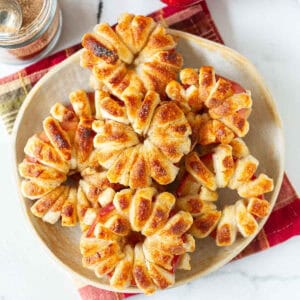 Puff pastry apple donuts stacked on a serving plate.