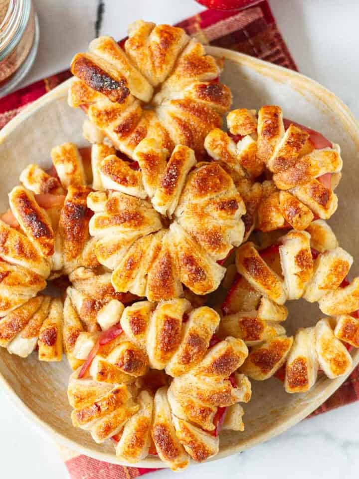 Puff pastry apple donuts stacked on a serving plate.