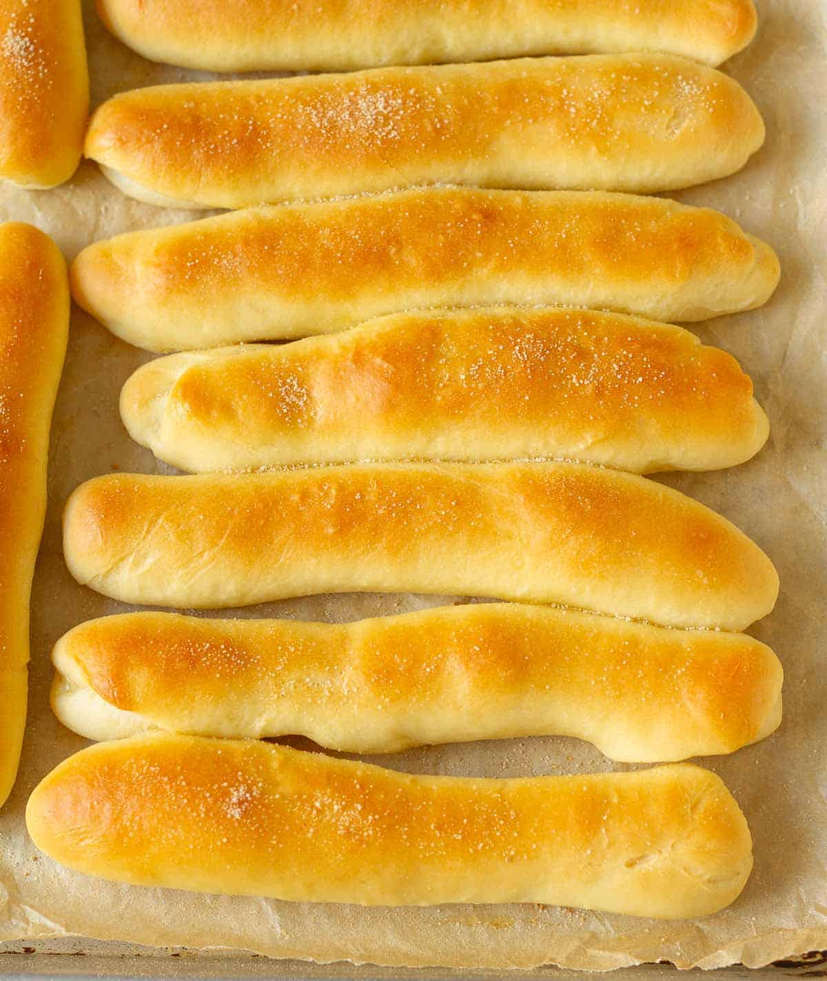 Bread sticks sprinkled with garlic salt on parchment paper.