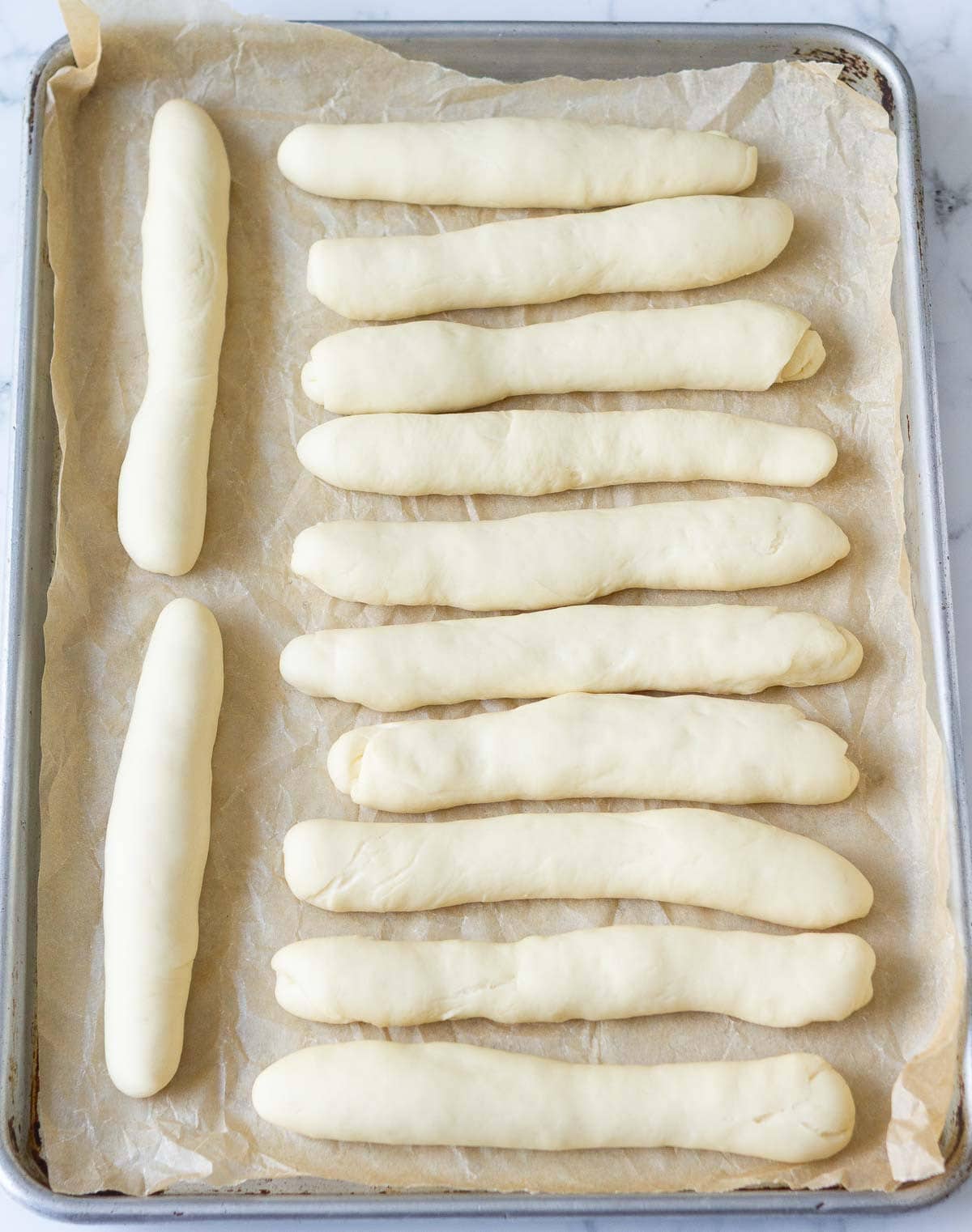 Proofed bread dough logs on a baking tray.