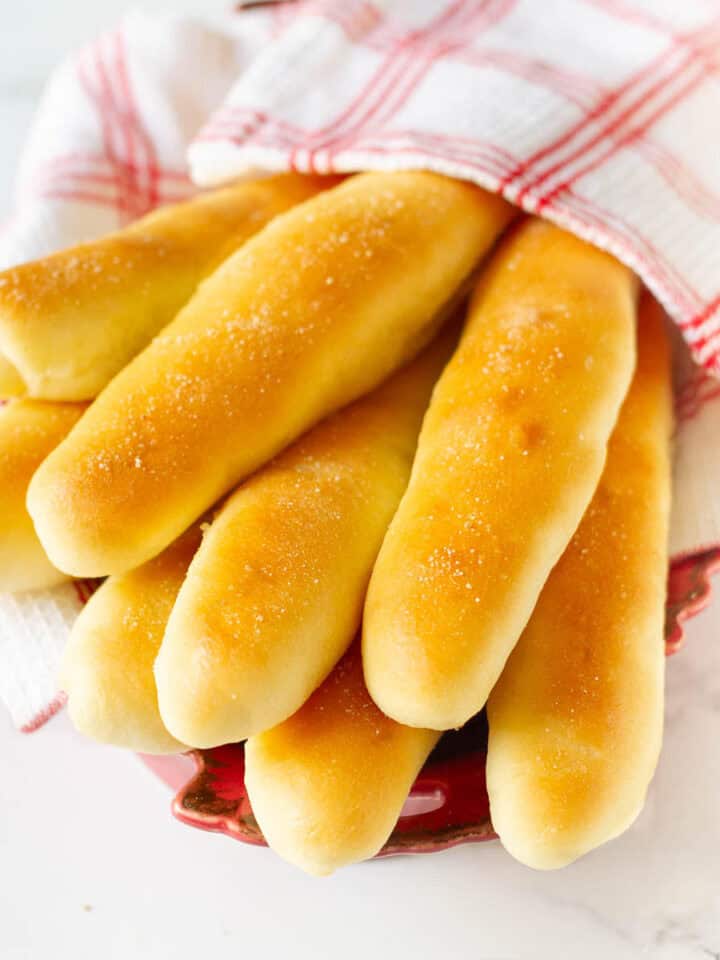Garlic breadsticks wrapped in a red and white kitchen napkin.