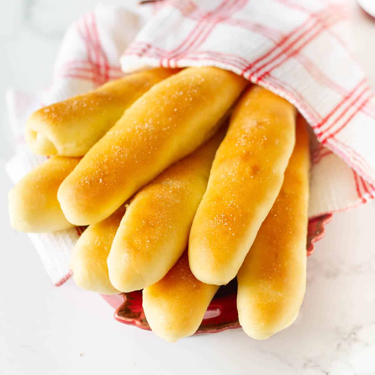 Garlic breadsticks wrapped in a red and white kitchen napkin.