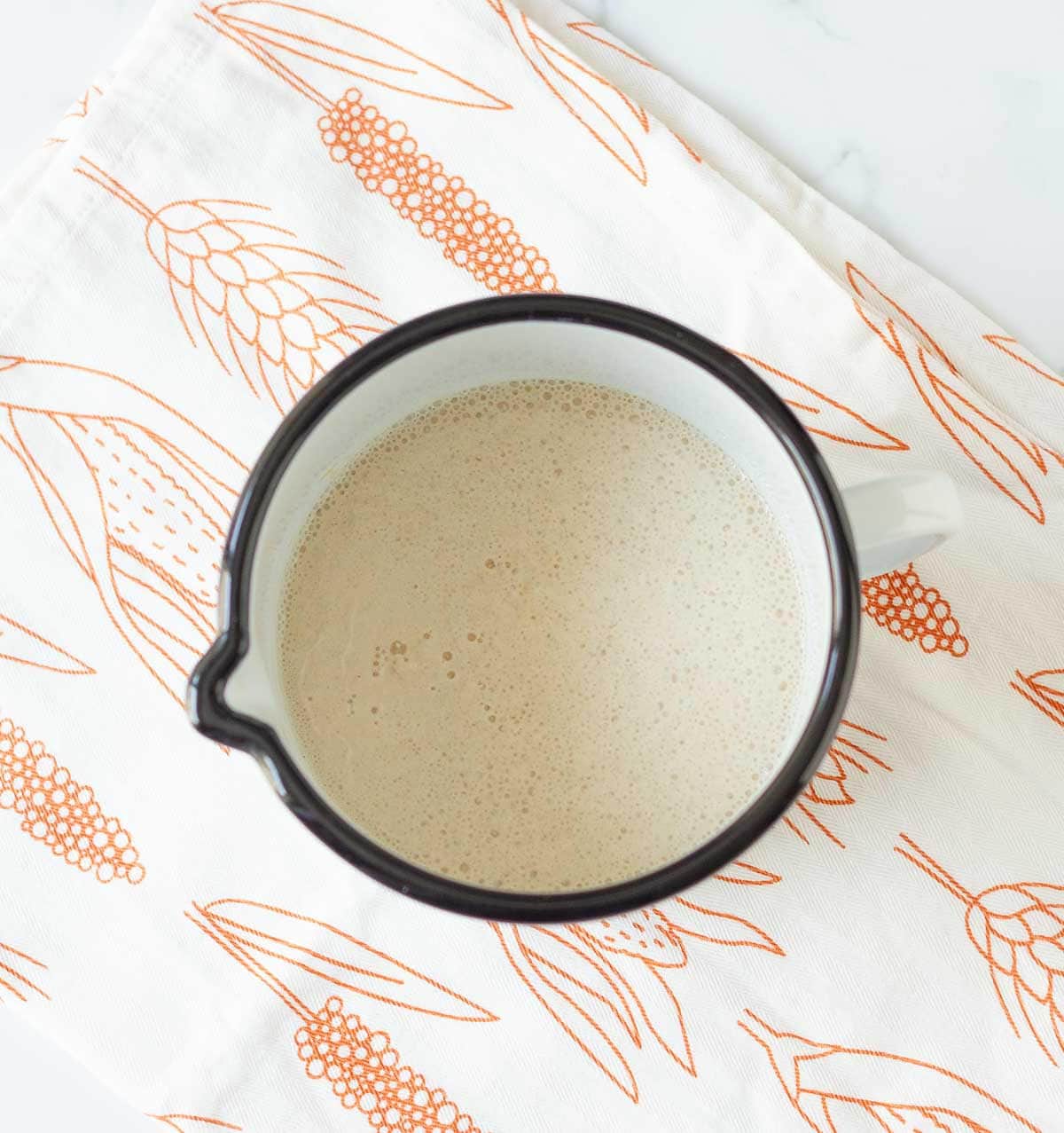 Bubbling yeast and water mixture in a measuring cup.