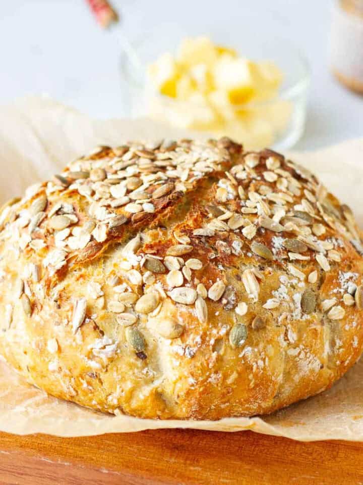 no knead seeded oatmeal bread loaf on parchment paper.