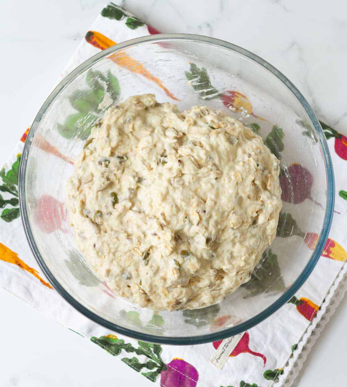 Dough for seeded oat bread in a mixing bowl.