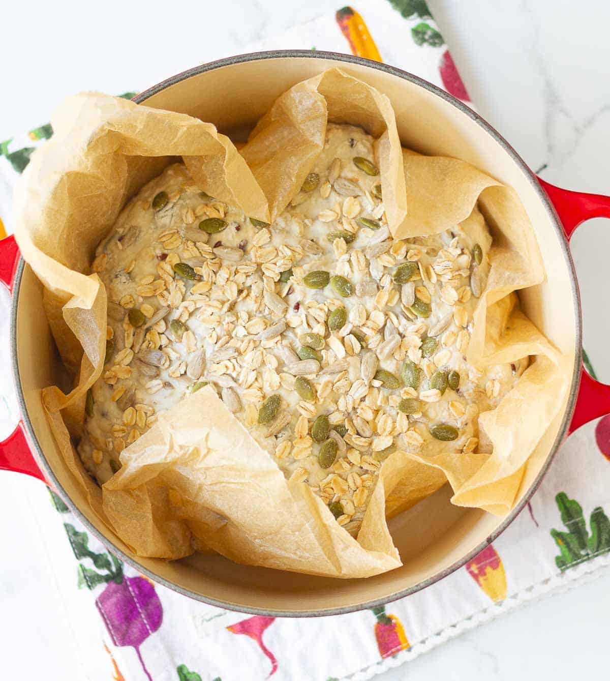 Bread dough in a Dutch oven on parchment paper.