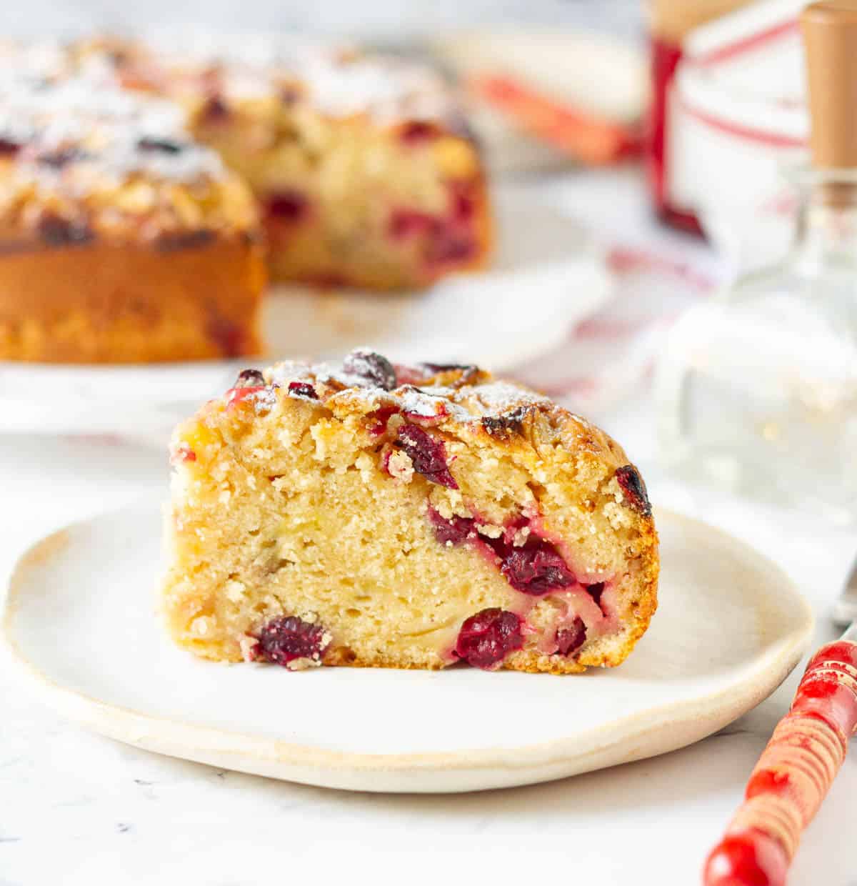 A slice of cake on a small plate with a red fork on the side.