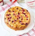 cake with apples and cranberries on a white plate on a white and red napkin.