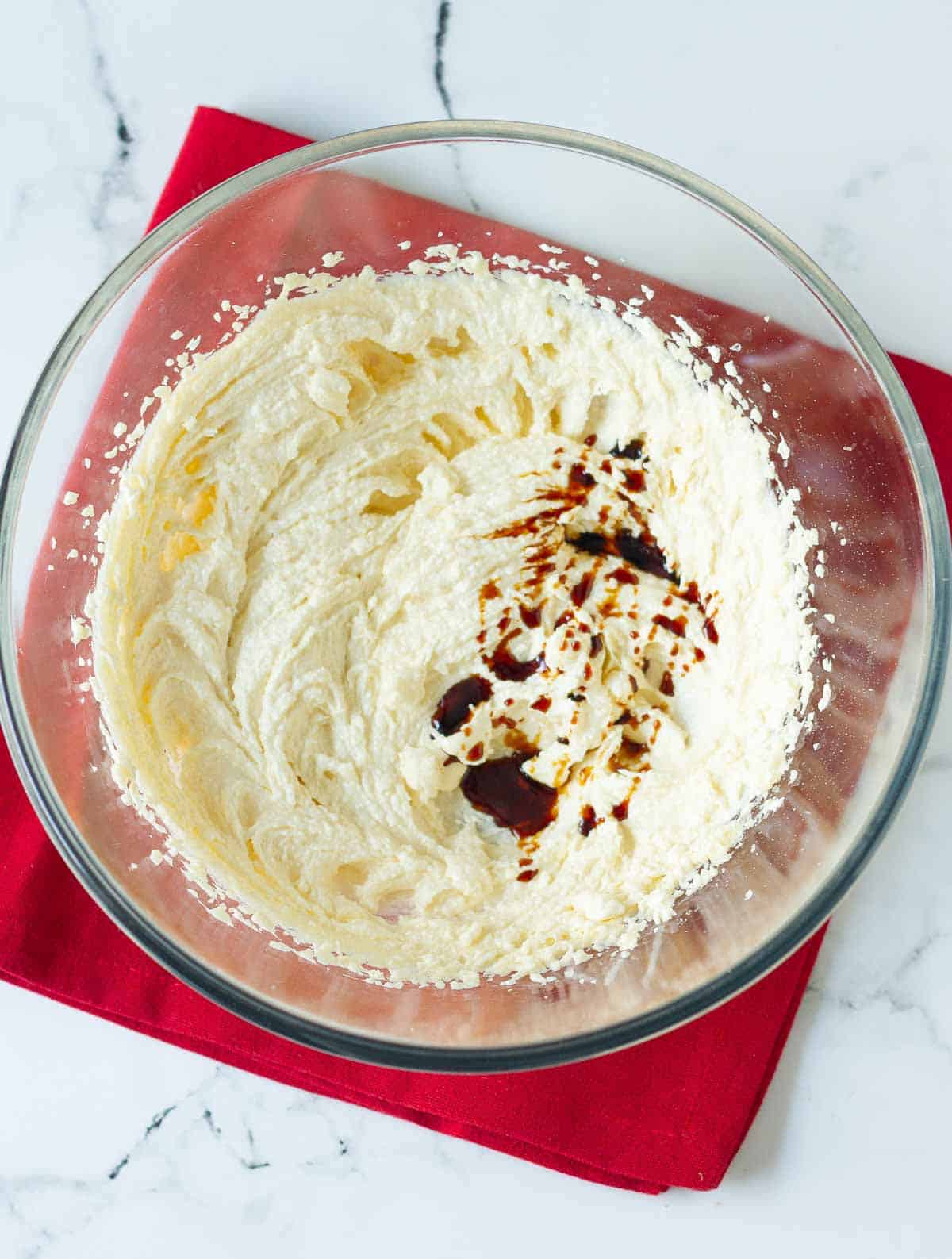 Vanilla extract on butter-sugar mixture in a mixing bowl.