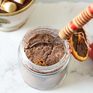 Hot chocolate mix in a jar with a spoon and twine with dried orange around it.