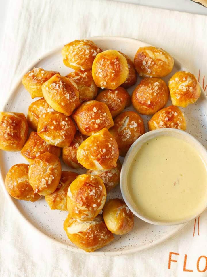 A platter full of pretzel bites with a small bowl of dip.