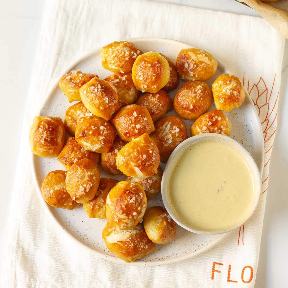 A platter full of pretzel bites with a small bowl of dip.