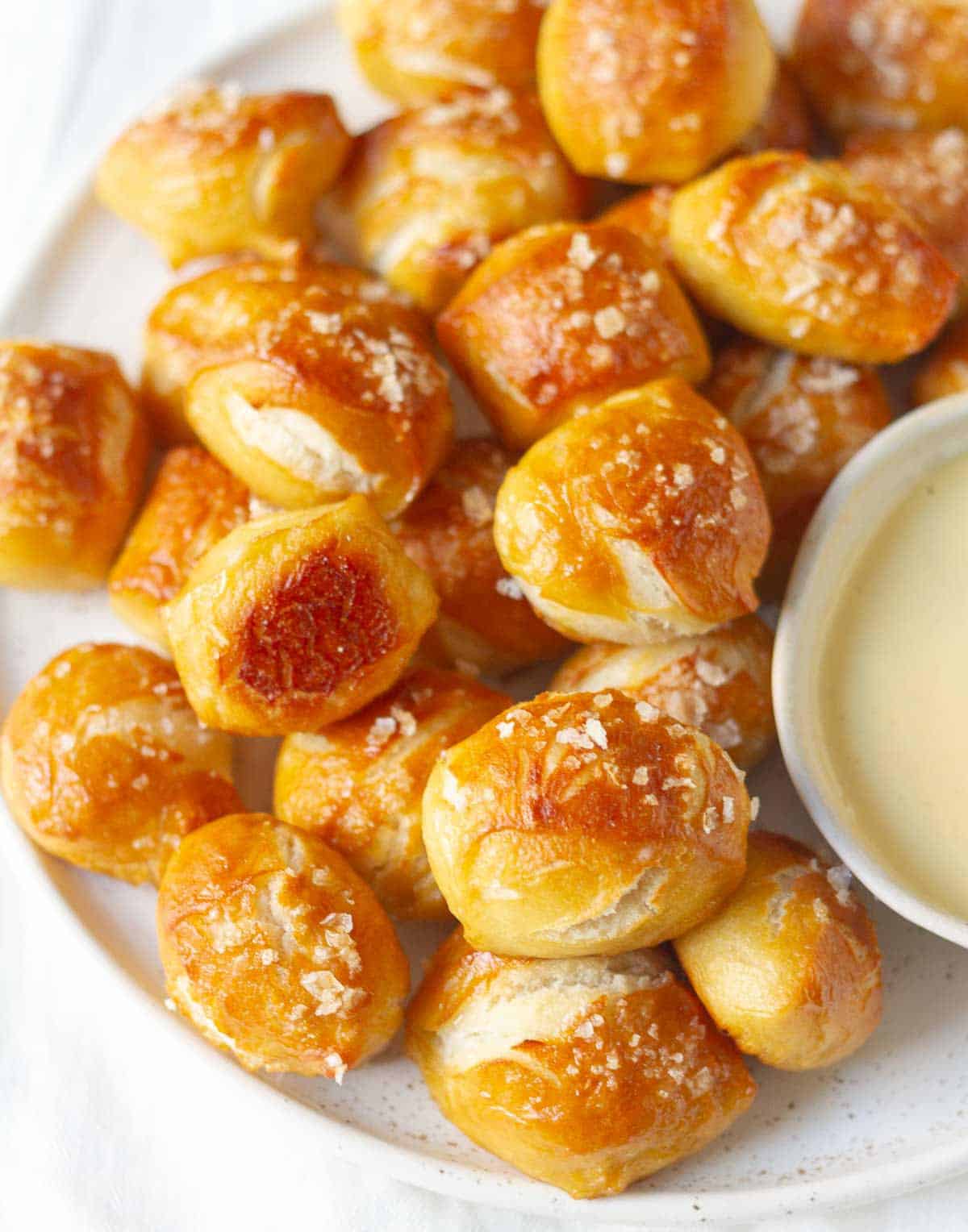 Golden pretzel bites on a platter with a sauce in a bowl.