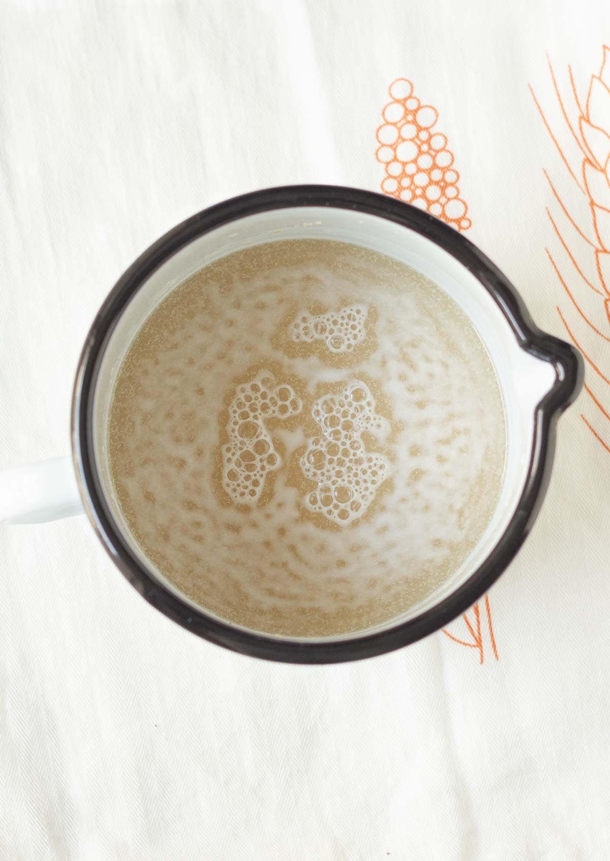 A measuring cup with foamy yeast water mixture.