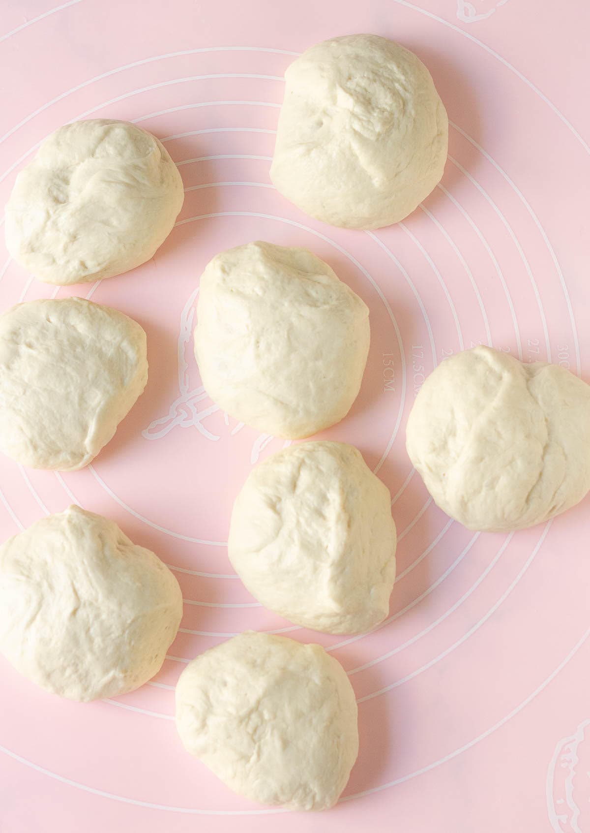 Dough divided into 8 pieces on a pink silicone mat.