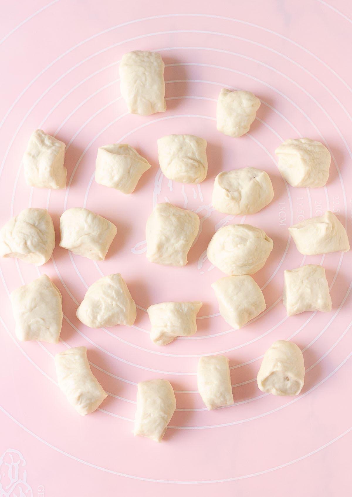 Dough cut into small pieces on a pink silicone mat.