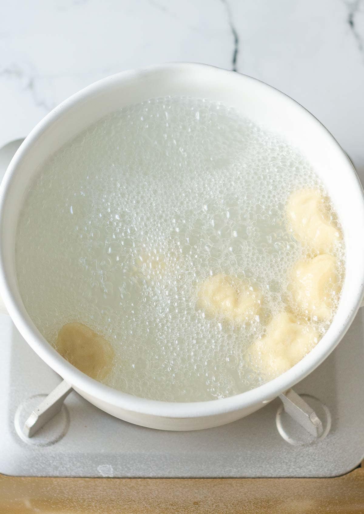 Dough pieces in a pot of boiling water.