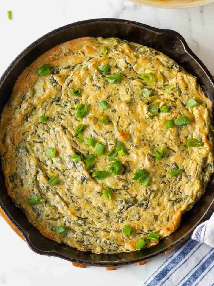 Baked vegan spinach artichoke dip in a cast-iron pan.