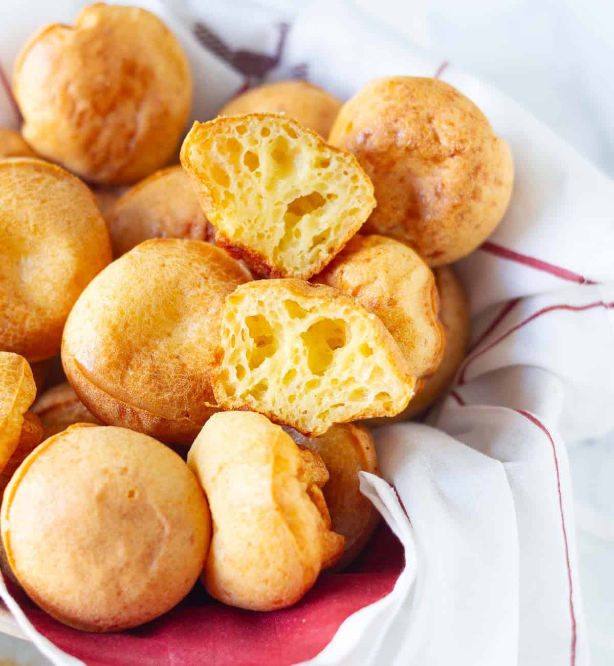 A bowl of bread rolls with one roll cut into half.
