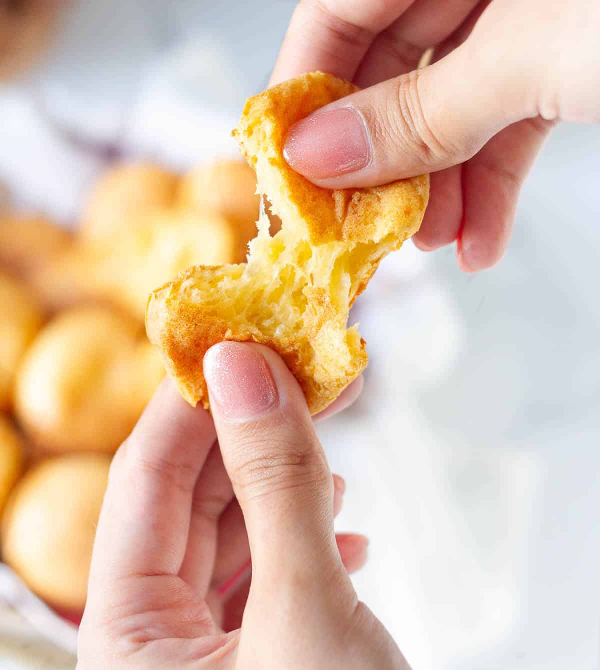 2 hands breaking a bread roll to show the chewy interior.