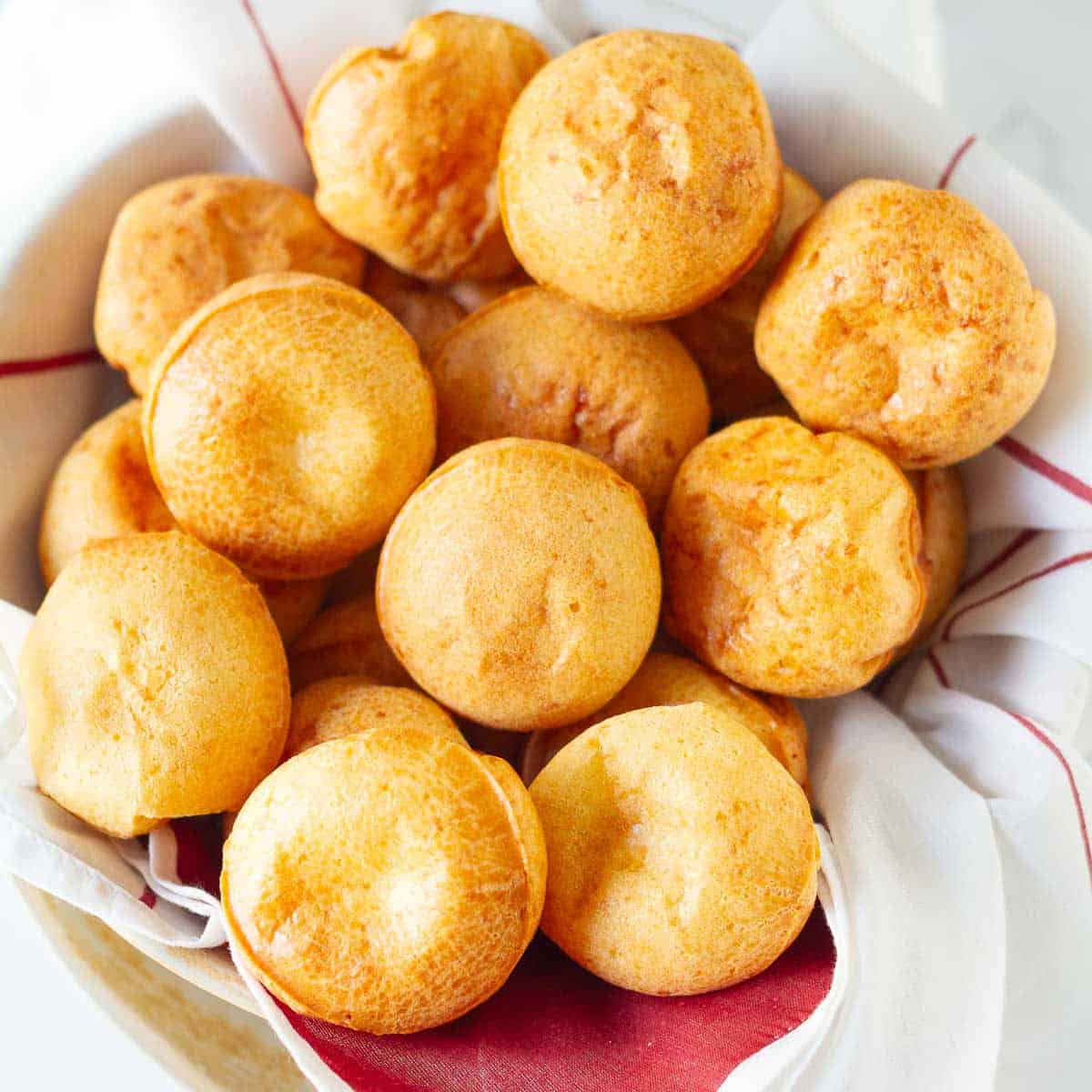 Brazilian cheese bread rolls in a bowl lined with red and white napkin.