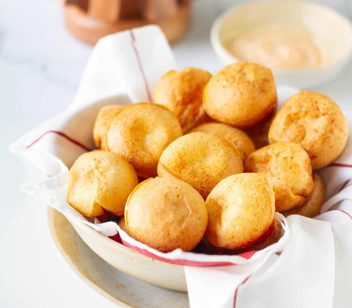 Bread rolls in a bowl lined with with red and white napkin.