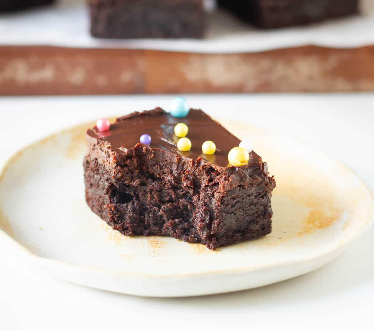 A half eaten brownie on a small plate.