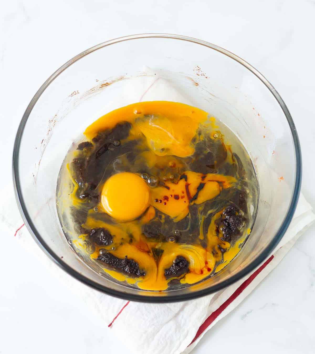 Eggs and vanilla extract on butter sugar cocoa powder mixture in a bowl.