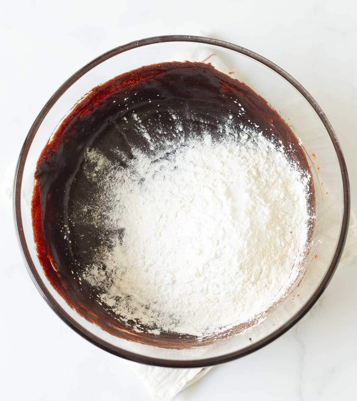 Flour on top of chocolate mixture in a mixing bowl.