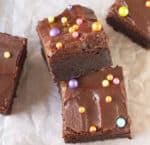 2 stacked pieces of brownies with chocolate frosting and sprinkles.