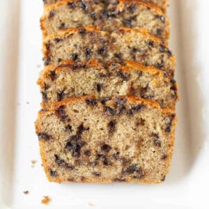 Sliced chocolate chip banana bread on a white platter.