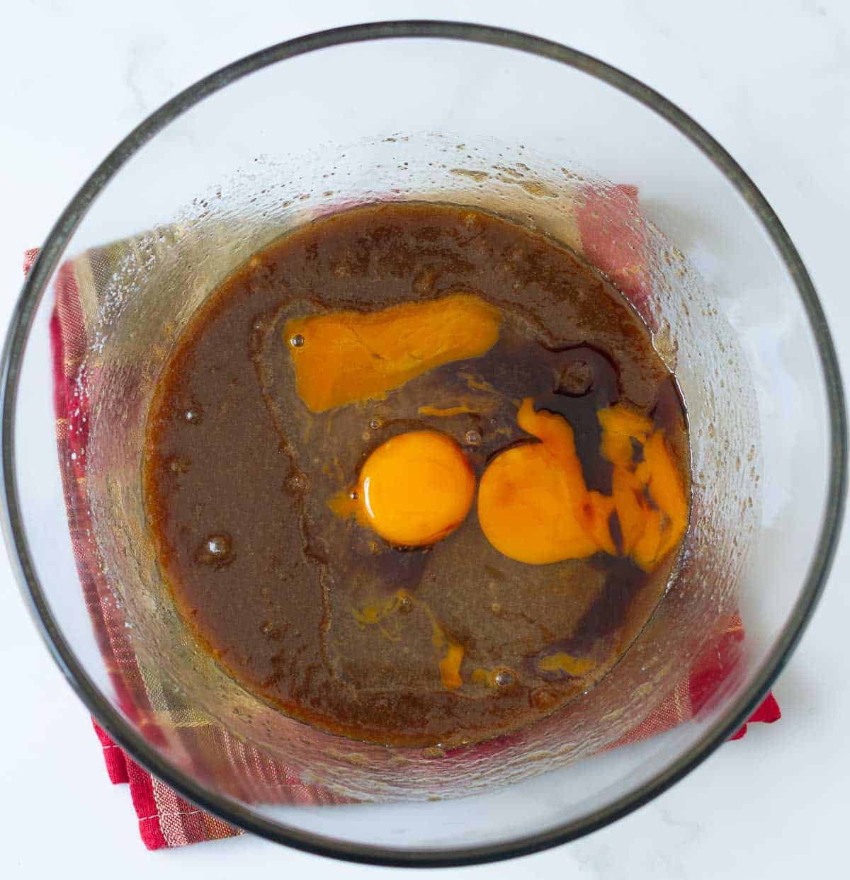 Eggs and vanilla extract on top of butter-sugar mixture in a bowl.
