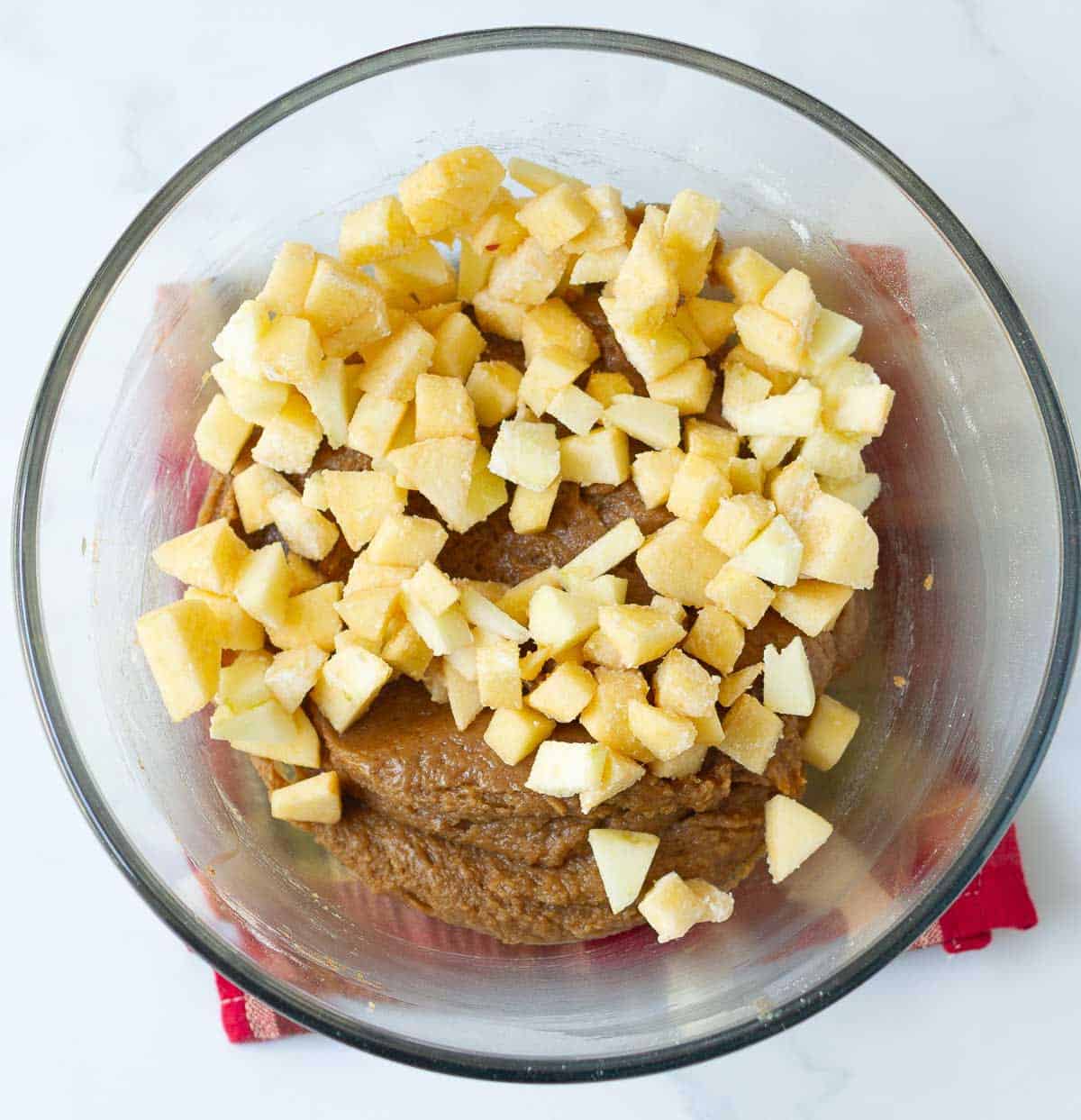 Diced apples on top of blondies batter in a mixing bowl.