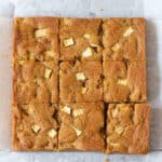 Apple blondies cut into 9 squares on parchment paper.