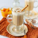 Homemade pumpkin spice latte in a mug topped with milk foam and cinnamon stick.