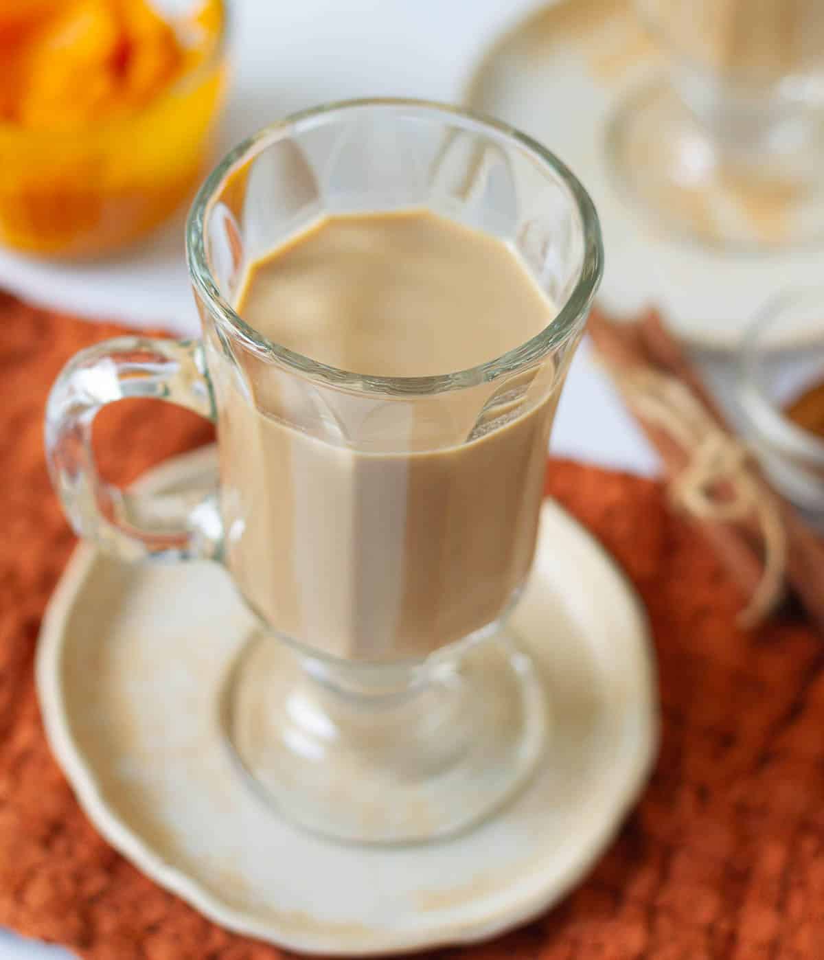 Pumpkin spice latte in a mug with ingredients around.