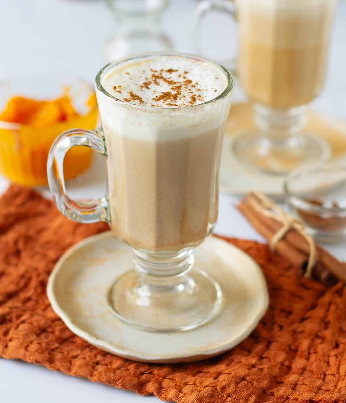 Pumpkin spice latte in a mug topped with milk foam, cream, and pumpkin pie spice.