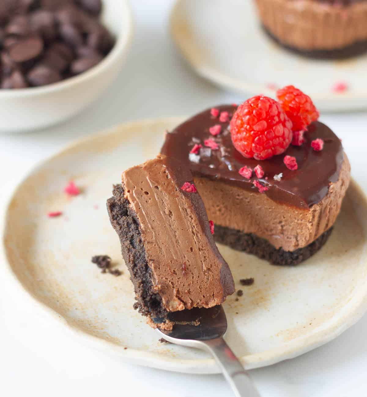 A bite of chocolate cheesecake on a fork on a plate.