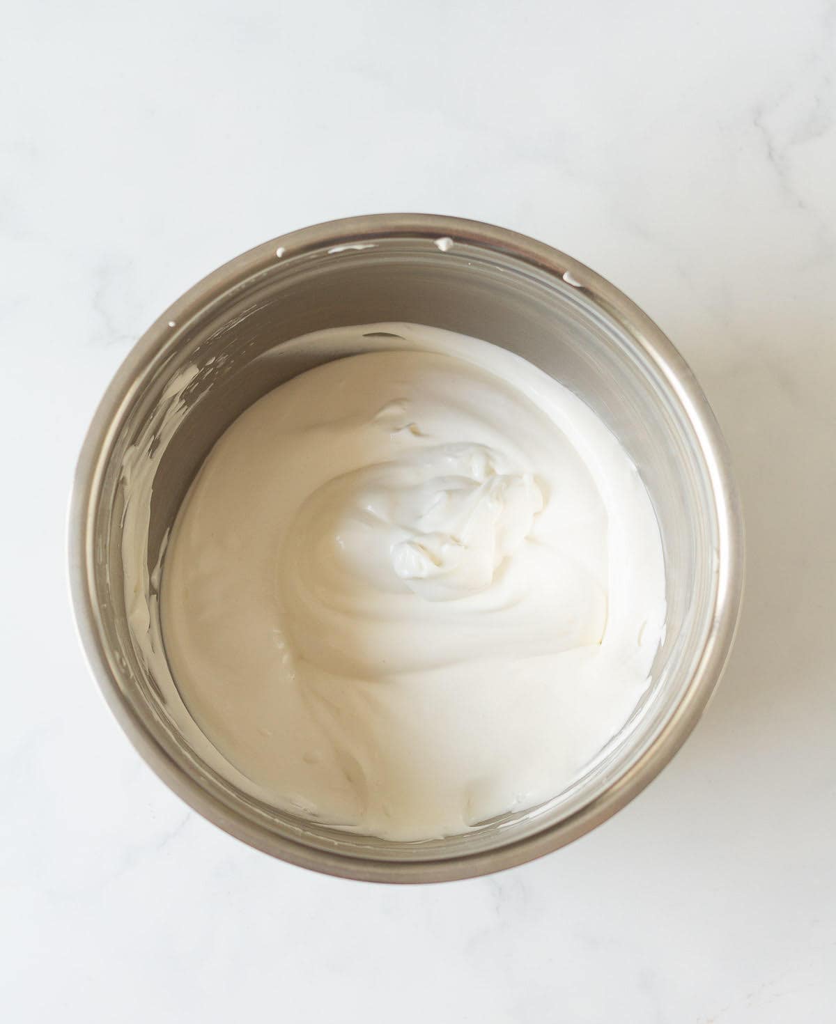 Whipped cream in a metal mixing bowl.