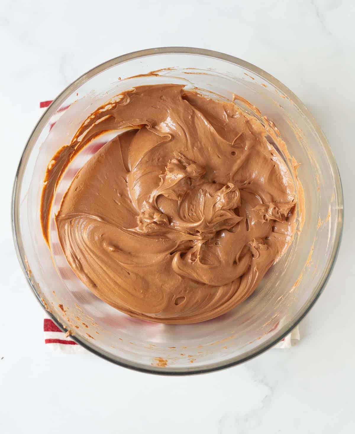 Chocolate cheesecake mixture in a glass mixing bowl.