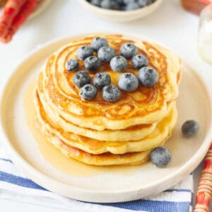 Sourdough discard pancakes stacked on a plate and topped with blueberries.