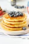 Sourdough discard pancakes stacked on a plate and topped with blueberries.