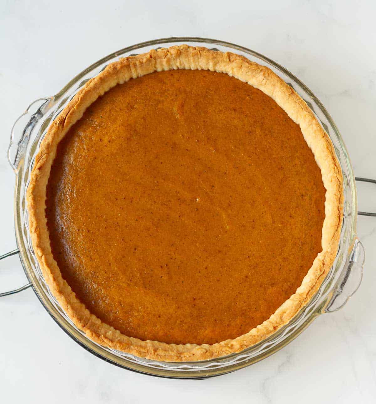 Baked eggless pumpkin pie in a pie dish on a trivet.