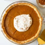 Sliced eggless pumpkin pie with whipped cream and pie spice on top.