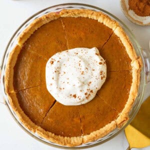 Sliced eggless pumpkin pie with whipped cream and pie spice on top.