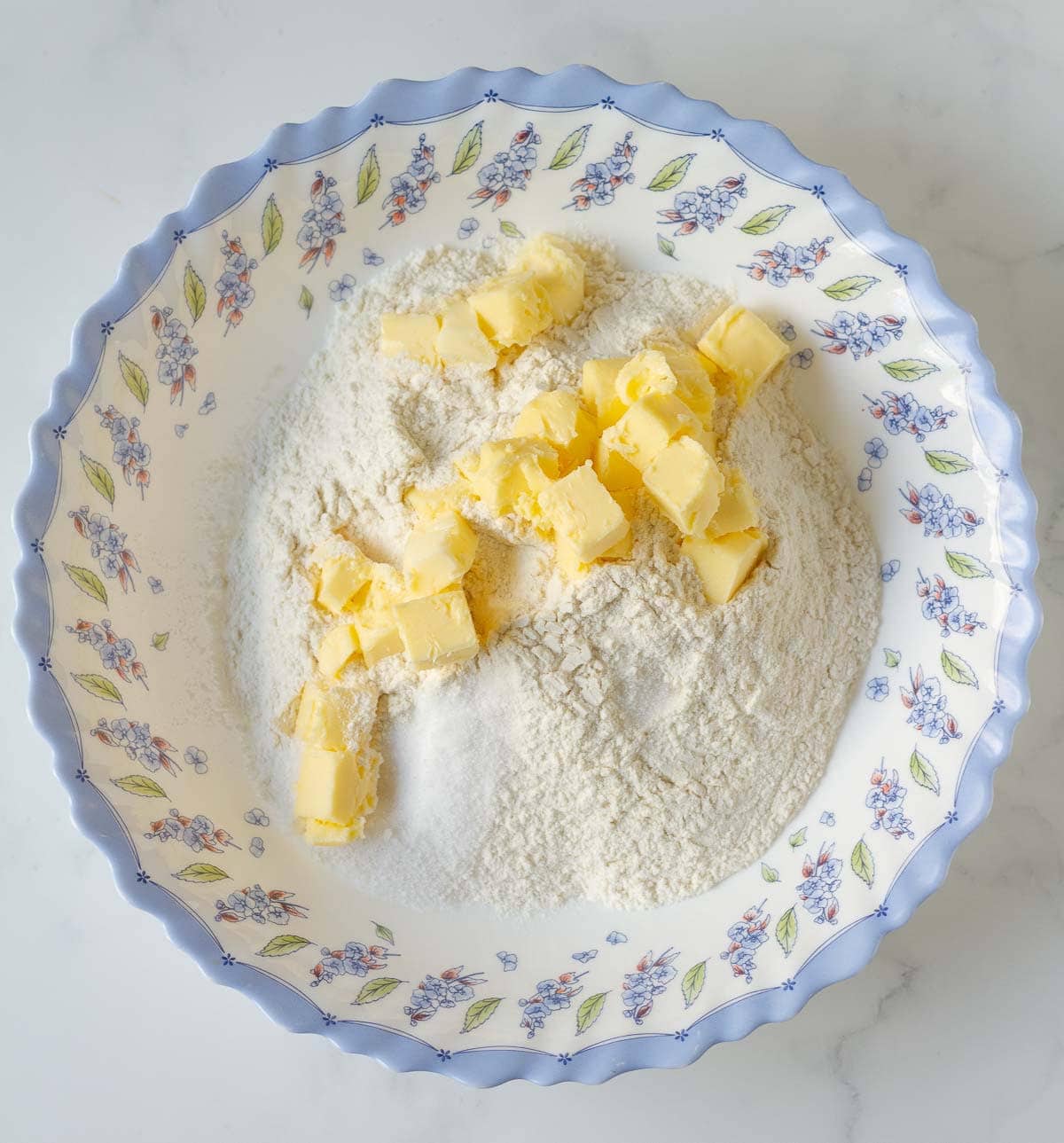 Cubed butter on flour in a mixing bowl.