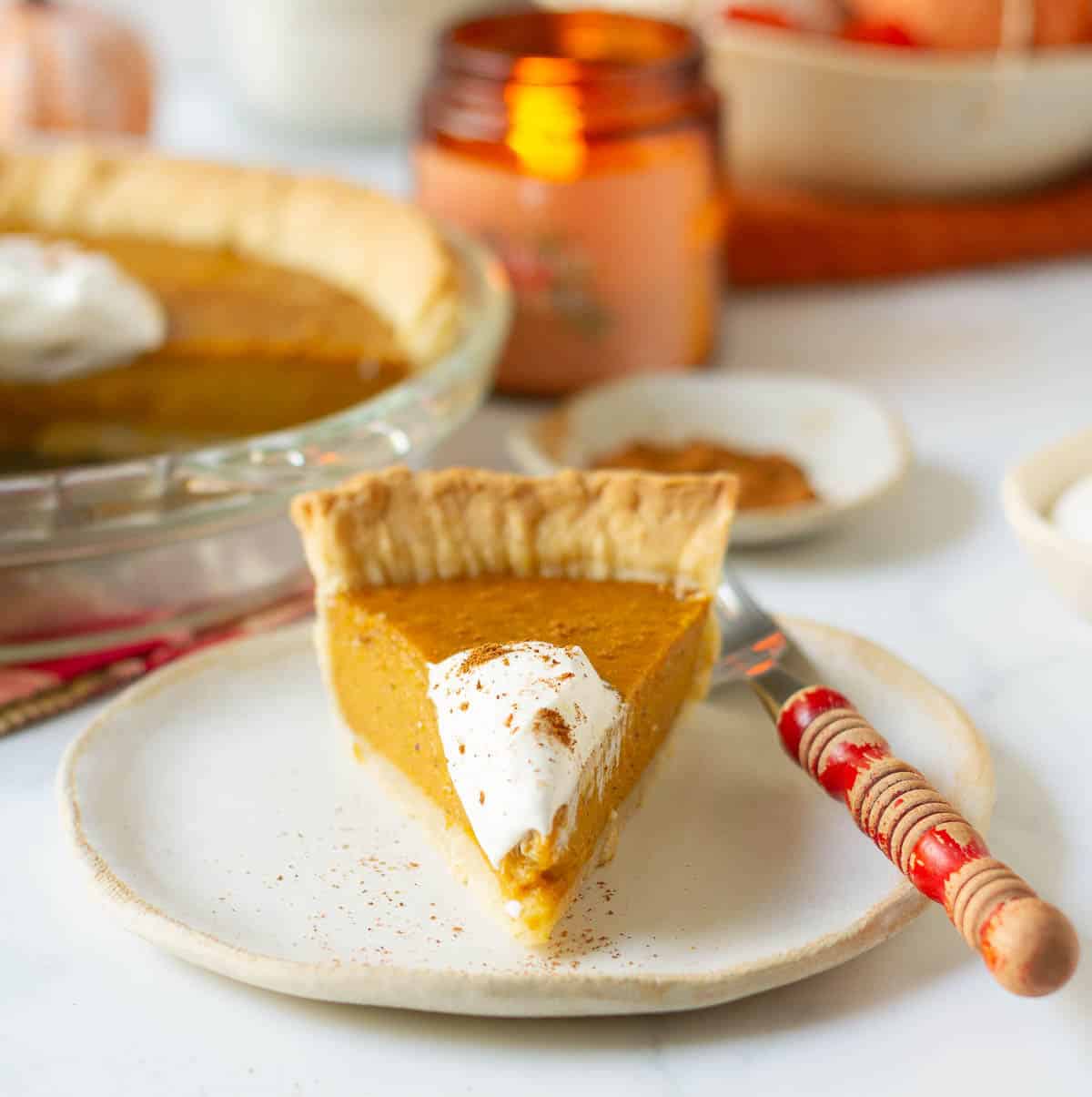 A slice of pie topped with whipped cream on a plate with a fork on the side.