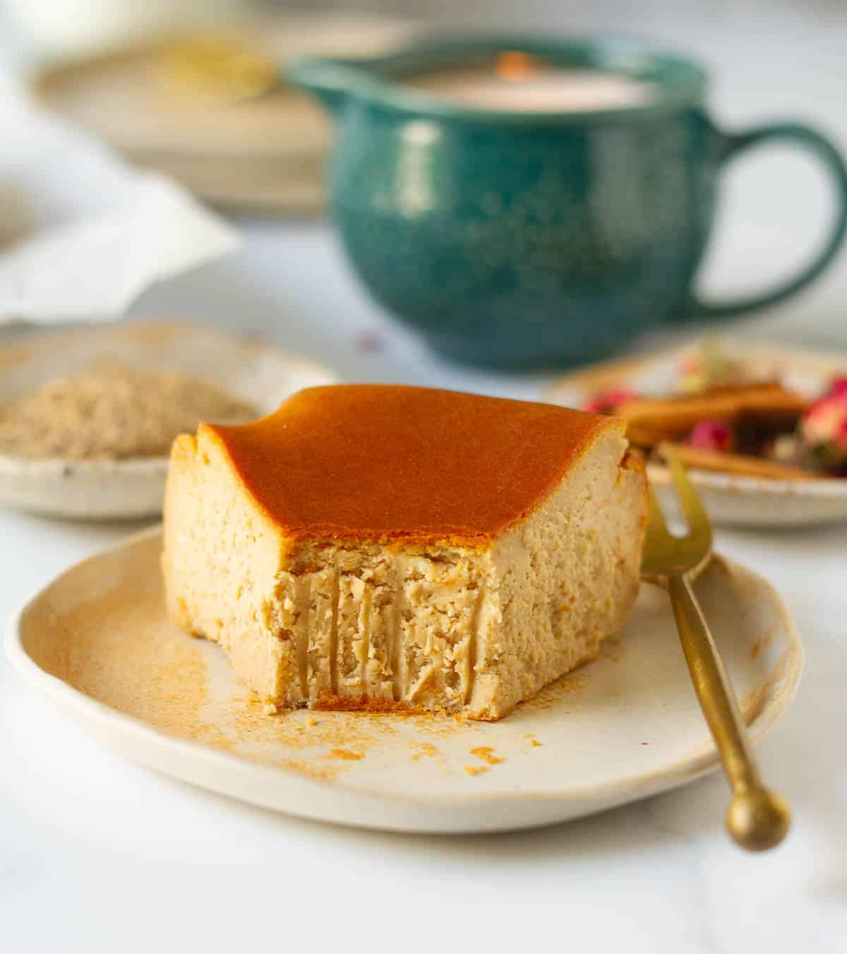 A slice of cheesecake and a fork on a plate with a bite taken.